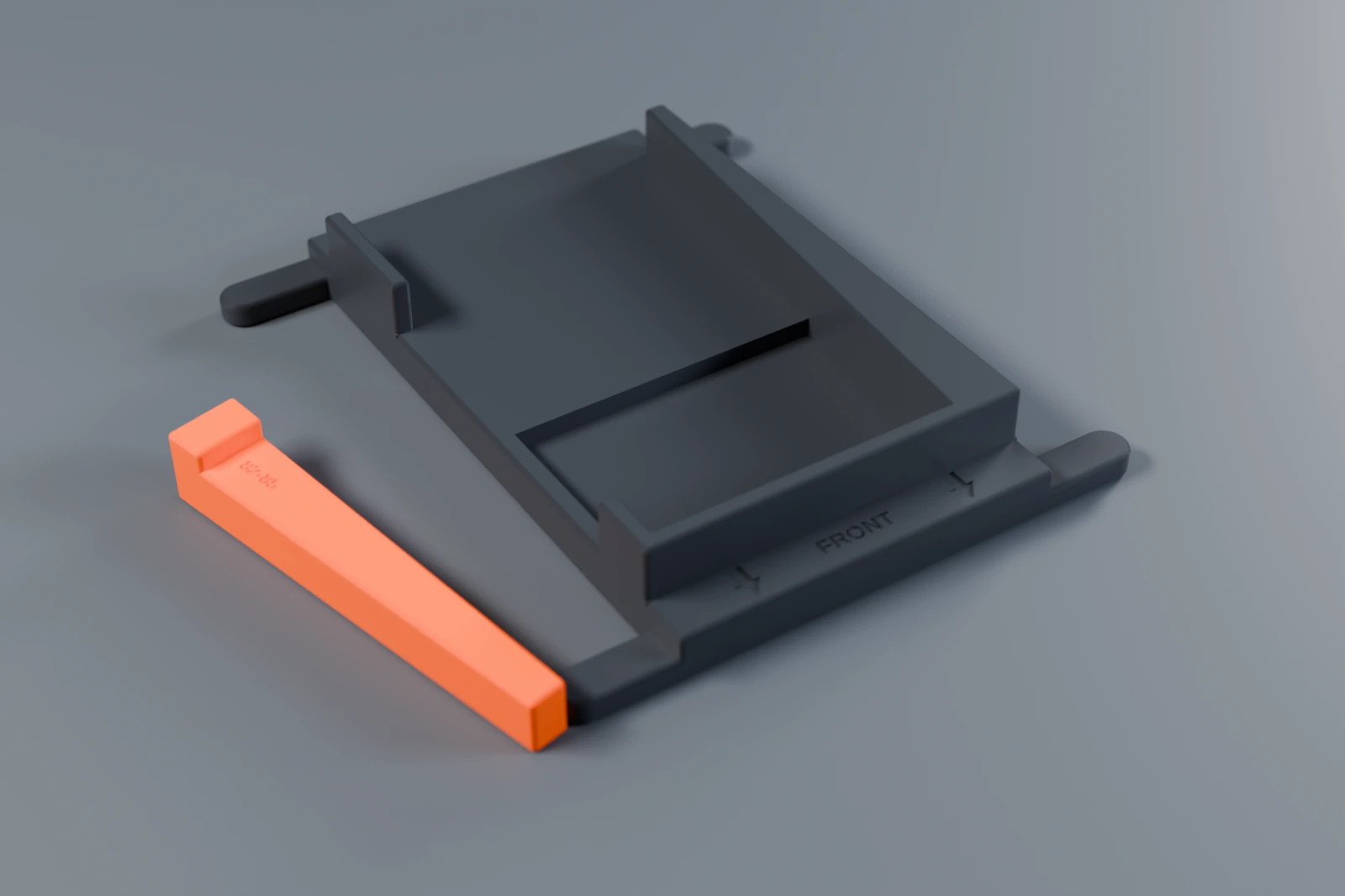 The empty bracket from above at an angle, showing the tray, the rail with its window, the end stop with FRONT engraved, the camera channel and the four prongs, with an orange wedge beside it